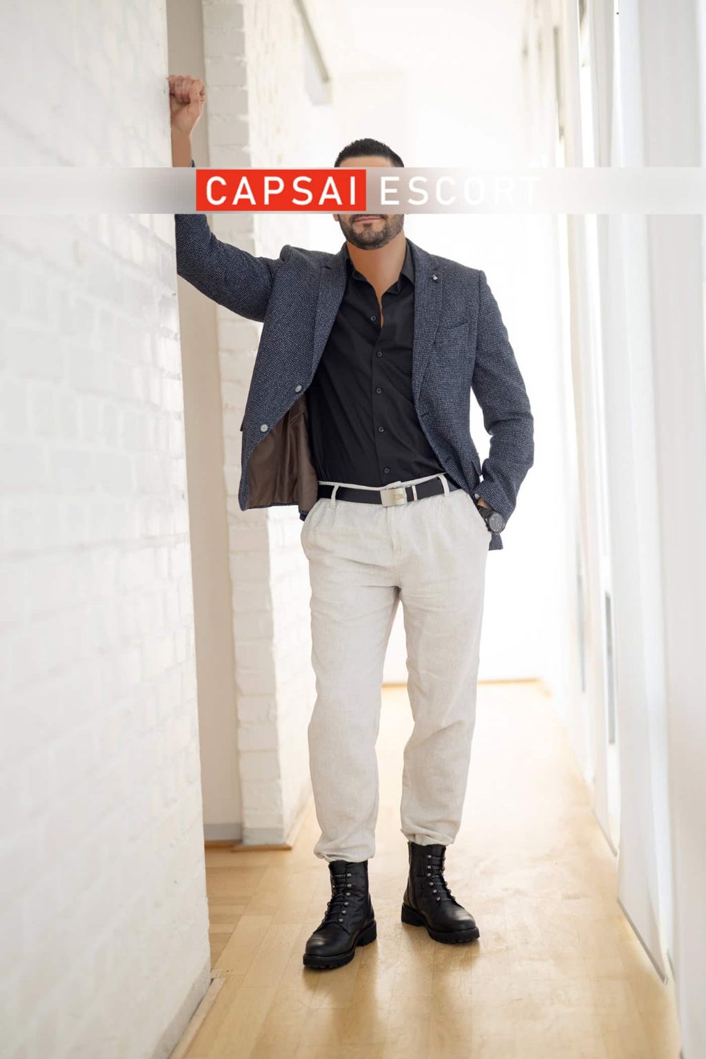 Carlos im Sakko an eine Wand gelehnt
