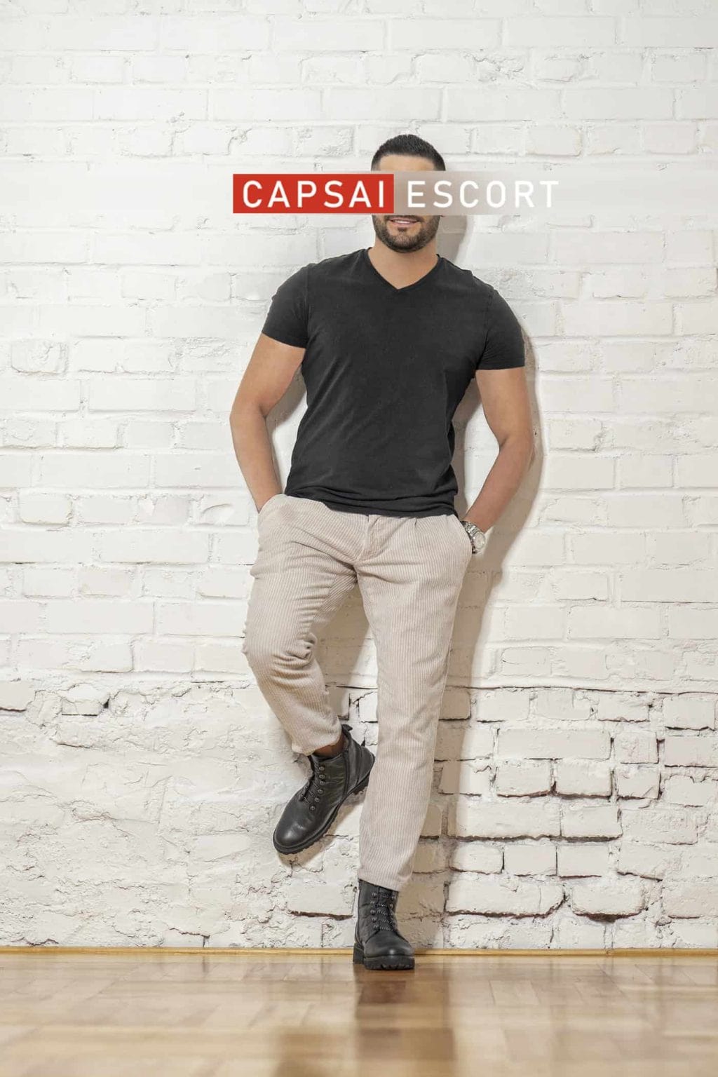 Carlos im schwarzen T-Shirt vor einer weißen Backsteinwand