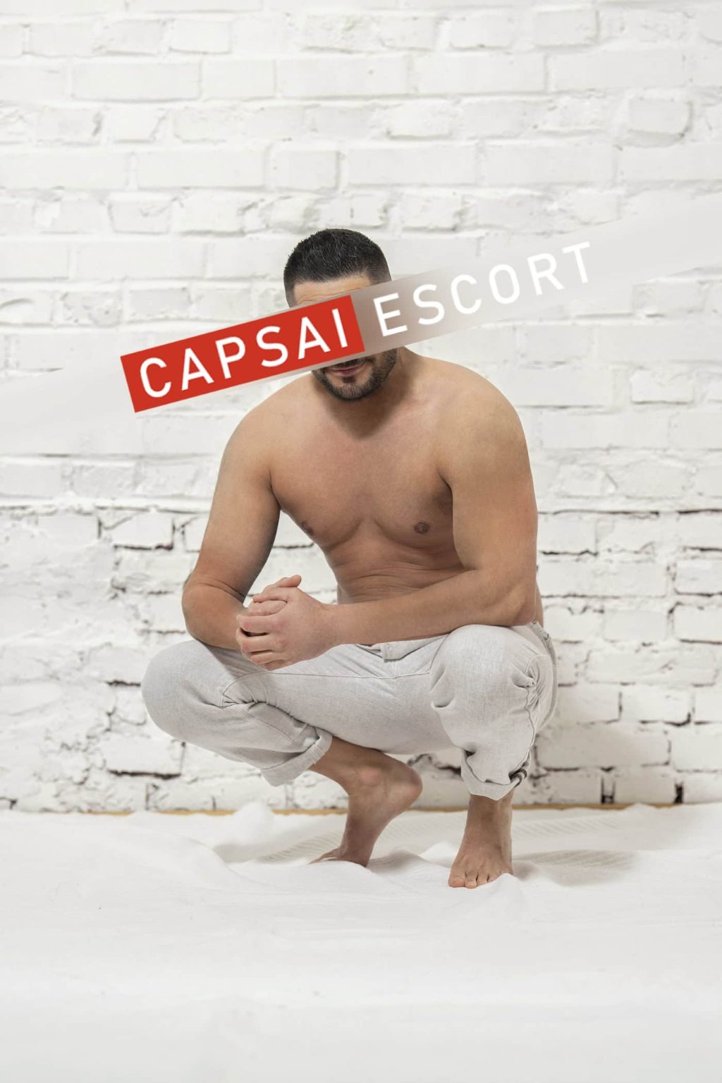 Carlos ohne Hemd vor einer weißen Backsteinwand