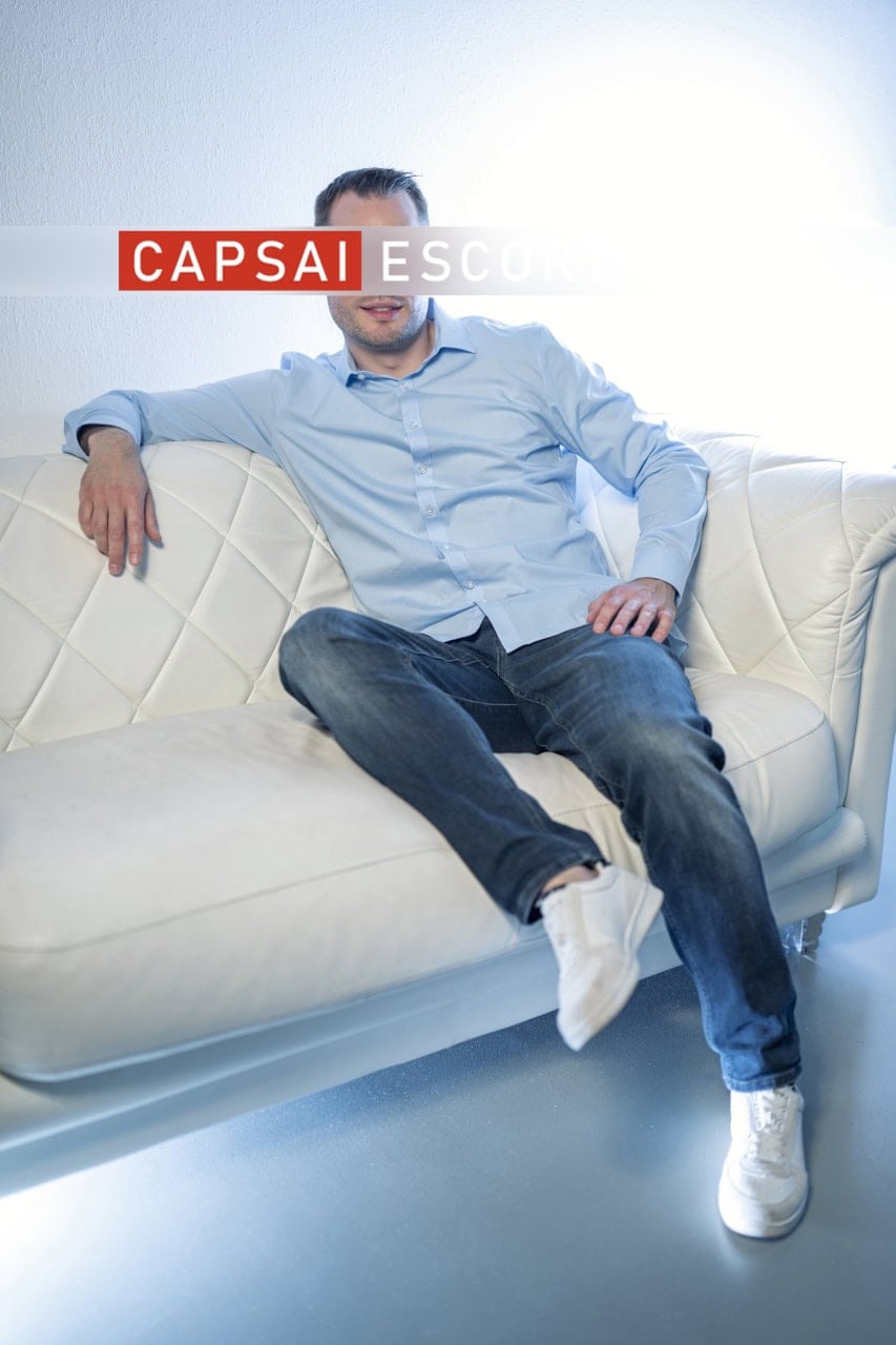 Noah im hellblauen Hemd auf einem weißen Sofa